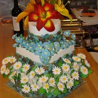 Tiered Garden Three tiered cake, fondant rock walls, gum paste daisies and day lilies, and royal icing flowers.