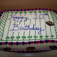 Football Field Whipped icing with sugar footballs around the sides (and one on top). The recipient is a New England Patriots fan, hence the blue & red...