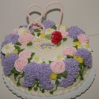 Birthday Cake 10 in Vanilla cake frosted with BC icing. The "87" and heart plaque are made from gumpaste. Purple flowers are BC. Roses, daisies...