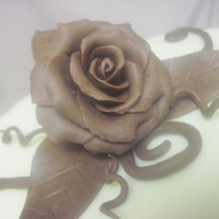 Chocolate Rose Red velvet cake with cream cheese frosting and covered in white chocolate ganache. Topped with a hand-crafted chocolate clay rose.