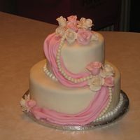 Gunter Wedding Cake covered in fondant with fondant swags, gumpaste roses, gumpaste string of pears with a light dry dust of pearl luster on pearls and...