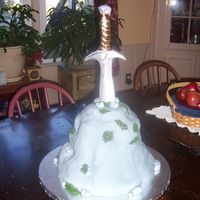 Sword In The Stone... Sort of a mixed theme, The kid wanted a Lord of the Rings sword stuck in a stone. Cake is covered in fondant with gumpaste sword.
