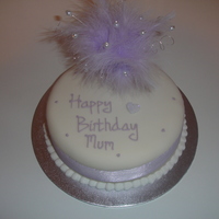 Lovely Lilac Round sponge cake covered in sugarpaste decorated with lilac feathers and pearls with a diamond. Very simple but pretty.