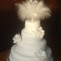 4 Tier White Wedding 4 tier white wedding cake, sponge, with decorative feather & heart topper, with 3 open roses on side.