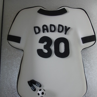 Daddy's Shirt Football shirt sponge cake covered in sugarpaste and decorated with a football and a pair of boots. Black & white ribbons.