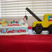 Oh Boy! Under Construction! quarter sheet covered with pastry pride molded chocolate and plastic decorations. crane is made with 2 loafs cut and stacked covered with...