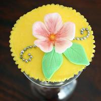 Yellow Flower Cupcake Buttercream icing topped with a fondant flower, leaves and silver cachous