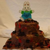 Max Mud Cake chocolate cake with chocolate frosting. gummy worms and cake crumbs for decorations. Max is made of gumpaste.
