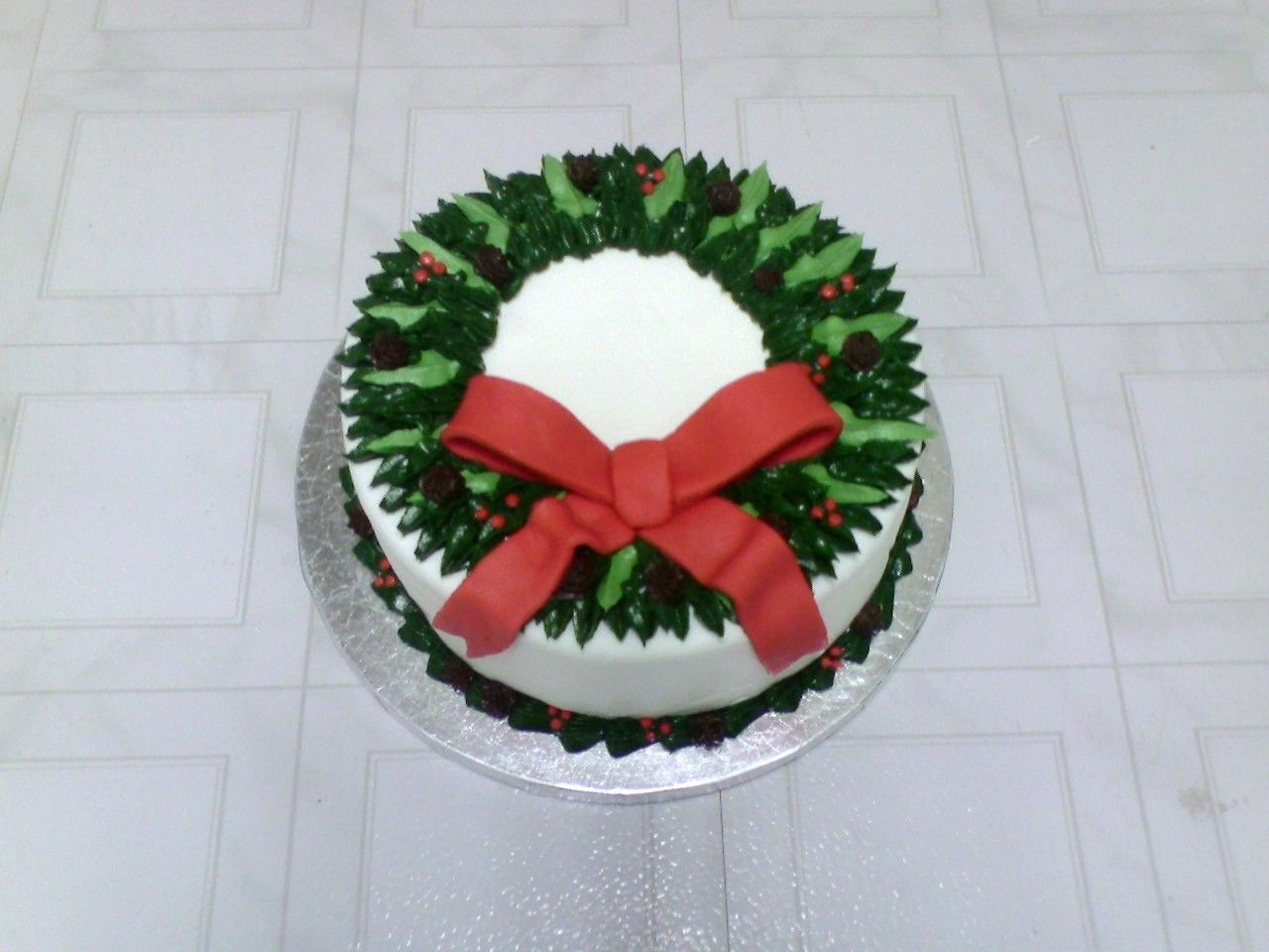 Holiday Wreath Cake White MMF w/buttercream greenery, pine cones and holly, fondant bow. I would change a few things next time.