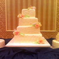 First Flowers This is a four tier ivory fondant covered wedding cake with two round satalite cakes. The scrollwork and beading are done in white...