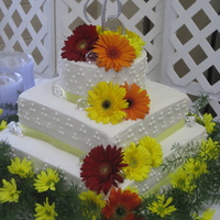 Gerbera Daisy Wedding Cake 16" square, 12" square, 8" round. Yellow cake, buttercream frosting. Live flowers.