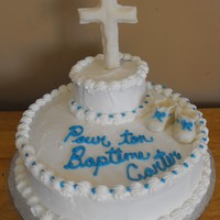 Baptism Cake Chocolate cake with buttercream and cross and booties are modeling chocolate .