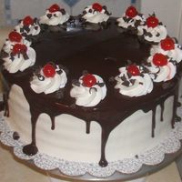 Cherry Ganach Cake White cake cherry filling iced with elgin whipped cream topped with ganach and decorated with marachino cherries and chocolate curls. It...