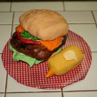 Burger Cake Actually... its not a cake.... its rice krispies!! The Buns and Burger are rice krispies covered in fondant, the Ketchup and Cheese are...