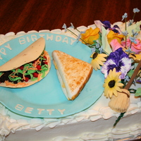 Betty's Cake White sheet cake iced and filled with buttercream; plate made of gumpaste; taco shell is gumpaste. "Meat" is brownie, crumbled;...