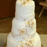 Pointsettia Wedding Cake 3 tier white cake iced in buttercream and covered with ivory fondant then piped with corneli lace; band of ivory fondant rolled around the...