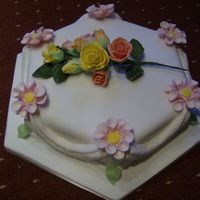 80Th Rose Hexagonal Sponge covered with fondant dahalias at each point with luster sprayed swags in between and a boquet of roses on top was made for...