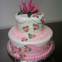 Lotus/cherry Blossom Cake 2 tier cake iced in buttercream with a fondant overlay on the top 1/2 of each tier. Lotus blossom and cherry blossoms and fondant.