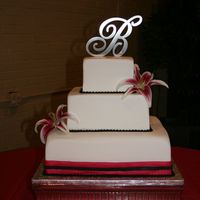 Simple Square Fondant Cake 3 square cakes wrapped in fondant, with fondant pearls and a fondant ribbon on bottom tier. Flowers are real. Colors are black and...