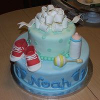 Baby Noah Tier cake with gum paste bow on top. Shoes, bottle, and rattle made out of gum paste.
