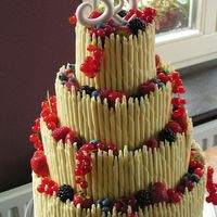 White Chocolate And Red Fruits Wedding cake, the sides decorated with white chocolate rolls and red season fruits on top