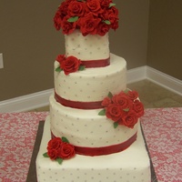 Red Roses Wedding white cake iced with vanilla butter cream icing. Silver dragees on the side. Roses and ribbon are made from fondant. Topper provided by the...