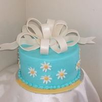 Daisies And Bow 8" cake with daisies and bowThis is iced with buttercream and has fondant bow and daisies :)
