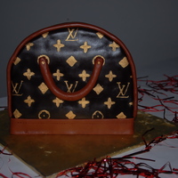Louis Vuitton Purse Cake Cake was covered in chocolate fondant and painted with gold luster dust and vodka. We made a stencil for it and then painted it on.