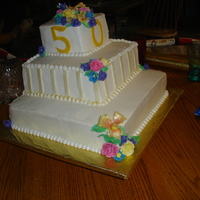 50Th Anniversary Anniversary cake with orchids, freesia, and roses made from gum paste. The stripes and the flowers were dusted with gold pearl dust.