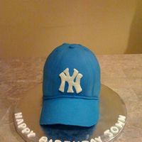 Ny Yankees Cap 1/2 sports ball on top of a 6" cake. Cakes covered with Fondant. Logo is made out of chocolate.