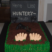 50Th B-Day Cake covered in buttercream, topped with crushed graham crakers and on the sides green buttercream. Feet made of gumpaste and headstone...