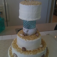 Beach Style Wedding 3 tiered traditional wedding cake, buttercream, candy chocolate seashells & brown sugar details. Top tiered separated by a sea themed...