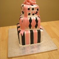 Stacked Present Cake Three tiered chocolate cake covered in white fondant with pink and black fondant decorations. Bow and ribbon made of fondant.