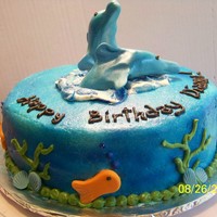 Dolphins In The Sea fondant hand-shaped dolphins, shells and fish. Butter cream covered cake airbrushed blue