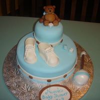 Teddy And Booties Baby Shower cake for a friend that is having a boy. Booties, Rattle, teddy, and blocks handmade from gum paste. The rest is fondant.