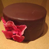 Chocolate Ganache Cake Chocolate genoise with ganache filling and chocolate glaze. Edible petals coated in sugar.