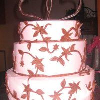 Pink/brown Heart Cake Round cake frosted in light pink buttercream. The flowers are made of chocolate fondant. The hearts are made of melted chocolate almond...