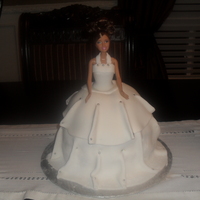 Doll Cake barbie doll cake covered in fondant . The cake is a 3 layer white cake made with lemon filling and buttercream .