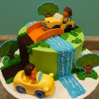 Dora And Diego Cake frosted in buttercream... purchased plastic toy cars, bridge and trees... road is made out of crushed oreo cookies