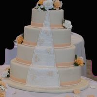 Peach And White This cake is iced in buttercream and covered in ivory fonant. The peach band and the pearls are fondant. The lace down the center is fonant...