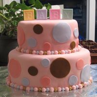 Baby Shower Cake 2 tier pink marshmallow fondant cake with multicolored pastel polka-dotsBead border is buttercream icing