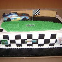 Nascar cake covered in fondant, car made of chocolate, barriers are vanilla wafer cookies, singns are edible images