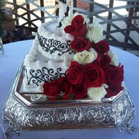 Black White And Red Wedding Cake Traditional vanilla wedding cake with butter cream icing. Black scrolls and fresh roses decorate the cake.