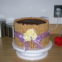 Mom's Birthday Cake 4-layer chocolate cake with chocolate icing. Surrounded with pirouline cookies. Silk flowers and ribbon.