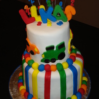 Colorful Birthday Cake For a big boy turning 2! Plane, car, pickup truck, firefighter truck, and train all around a very colorful yummy chocolate cake! Letters...