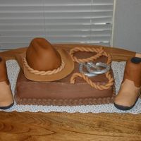 Little Cowboy's 1St Birthday Chocolate cake with chocolate whipped frosting. Hat and boots are molded rice crispies covered in fondant. Rope and horseshoes are fondant...