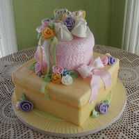 Stacked Baby Gifts Embossed fondant covers both packages and the serving board. Sugarpaste baby shoes and braclet are nestled among ribbons and ribbon roses....