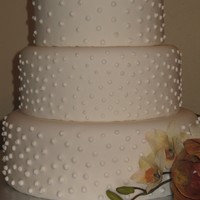 Dotted Wedding Cake Fondant covered ivory colored wedding cake. Decorated with Royal Icing dots and fake flowers.