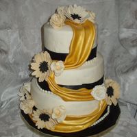 Black And Gold Chocolate WASC and regular WASC with chocolate cream filling, IMBC under fondant . All fondant and gumpaste flowers. Fondant swag in gold....
