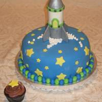 Rocket Cake Chocolate cake with coordinating chocolate cupcake. Rocket is sculpted from rice krispies and covered in fondant and gum paste.